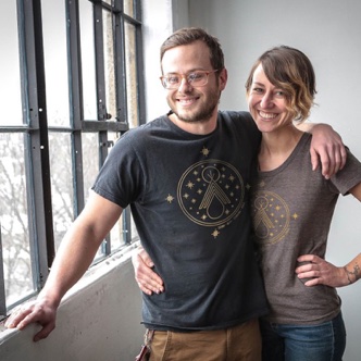 Kyle and Quelcy smiling whilst wearing their Stand with Standing Rock t-shirts.